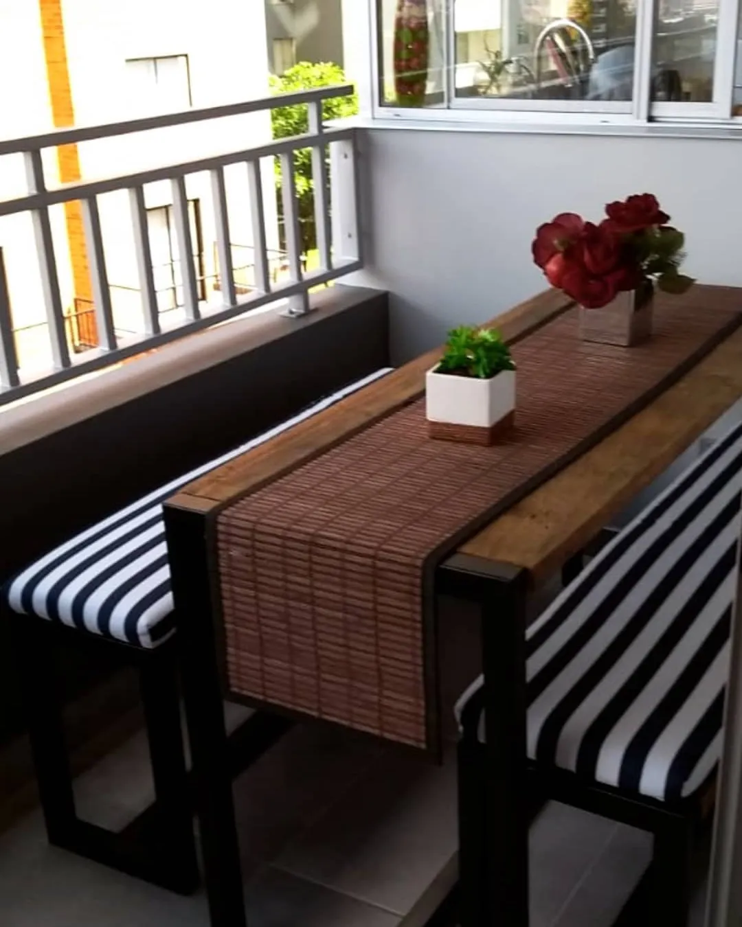 Mesa alta con dos bancas en el balcón de un apartamento
