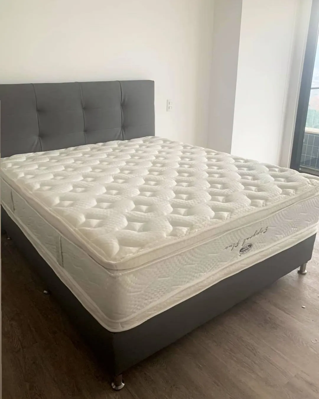 Cama doble con cabecero capitoné gris en un apartamento