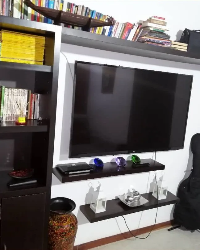 Librero y mueble de televisión en madera, en una sala con pared en ladrillo