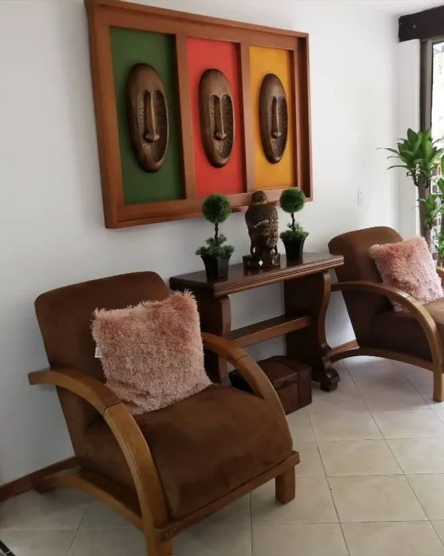 Dos sillones en madera con cojines, en la sala de una casa