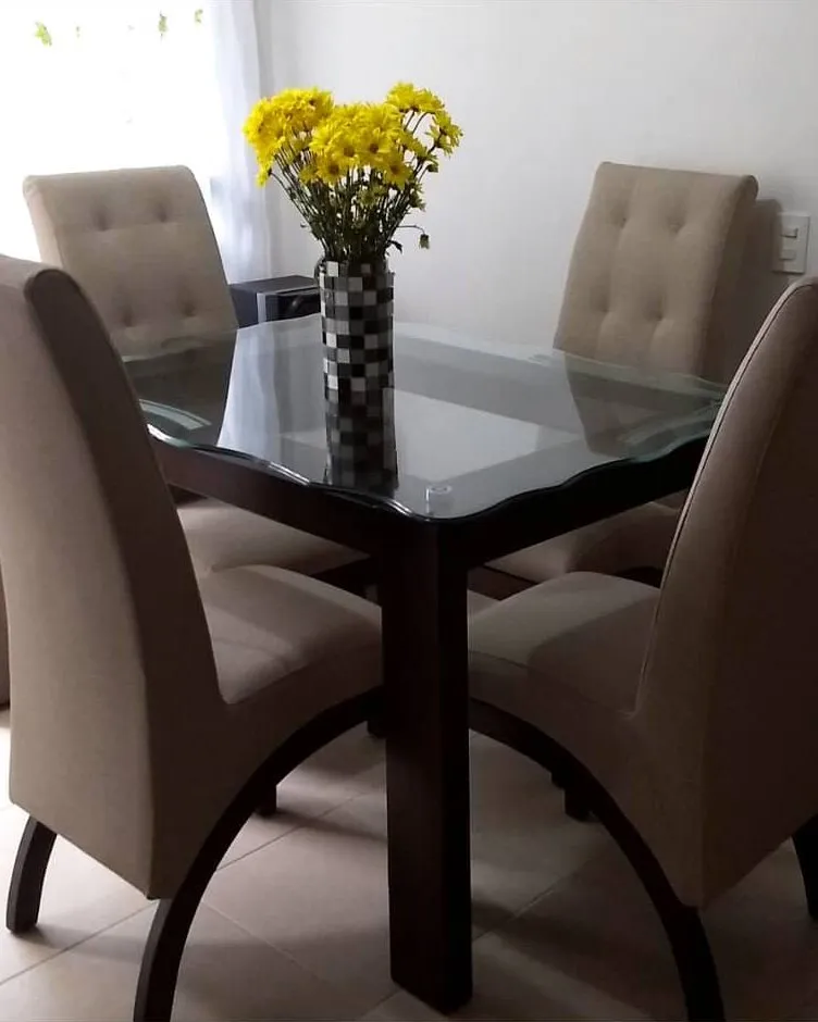 Comedor de cuatro sillas tapizadas en beige, con mesa en madera y vidrio
